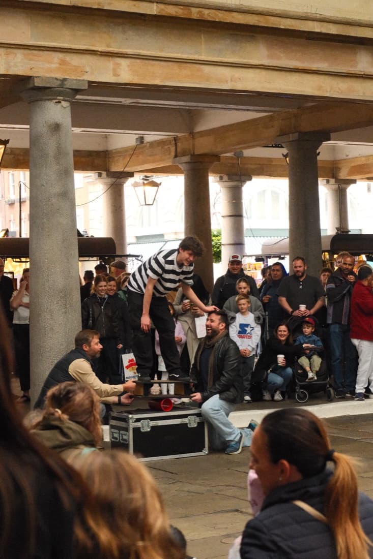 A crowd gathered around a street performer in a covered market