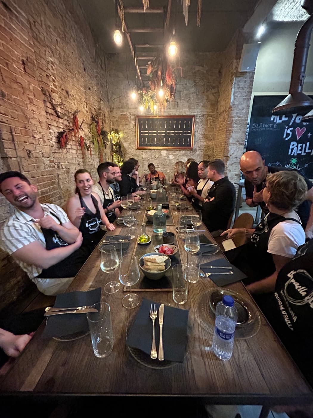 A long table of people laughing together at a paella cooking class
