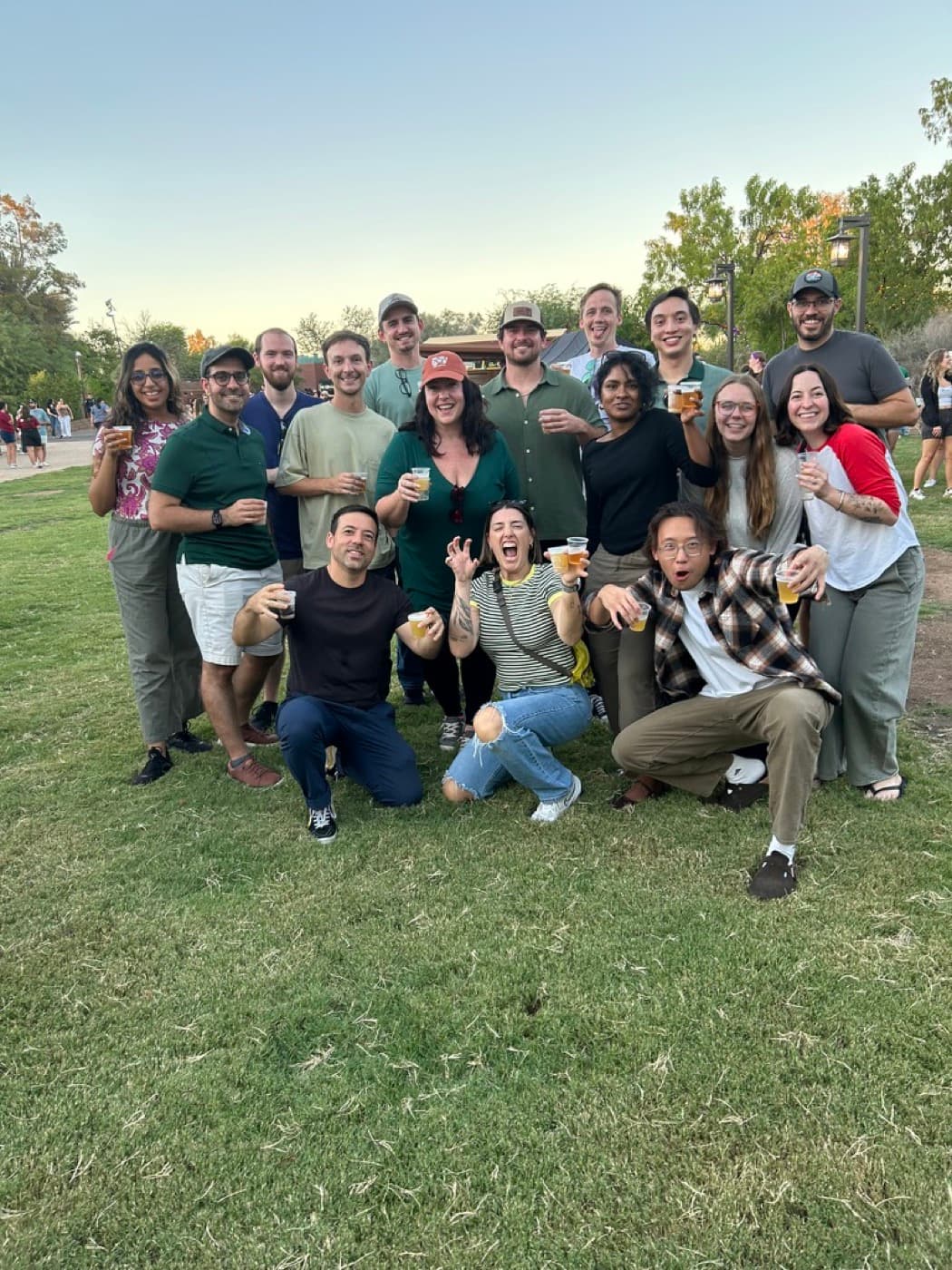 A large group at Roars and Pours at the Phoenix Zoo, drinks raised at golden hour
